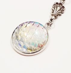 This beautiful mermaid inspired necklace is simply magical. The focal is an iridescent textured fish scale pendant that changes colour from opalescent whites to the palest of aquas and golden peaches depending on how the light reflects off its surface.  It's mesmerising. The pendant resembles a mermaid's tail with its scaly texture.  I attached the pendant to a beautiful sterling silver plated connecting component in shape of a delicate shell. The pendant is suspended on a 45cm stainless steel b Scale Necklace, Necklace Dragon, Sea Siren, Mermaid Inspired, Inspired Necklace, Fish Scale, Beautiful Mermaids, Mermaid Necklace, Fish Scales