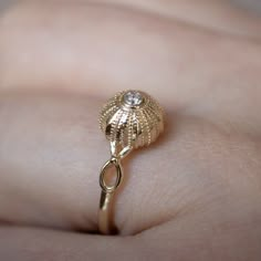 a close up of a person's hand holding a gold ring with a diamond