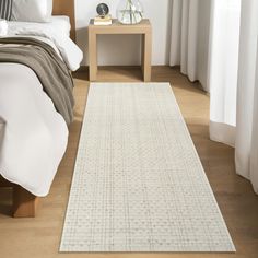 a white rug on the floor next to a bed