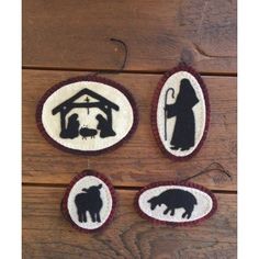 three nativity ornament ornaments with black and white silhouettes on wood background