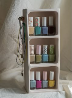 a white shelf filled with lots of different colored nail polishes and other cosmetics items