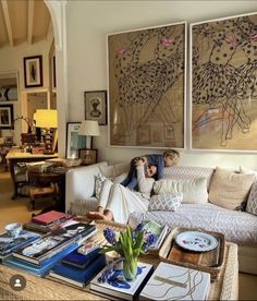 a living room filled with furniture and paintings on the wall above it's coffee table