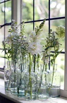 vases filled with white flowers sit on a window sill in front of the windowsill