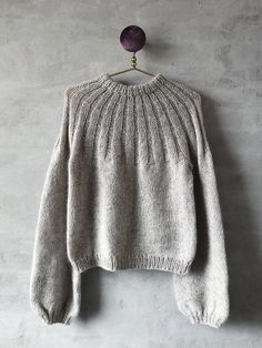 an old sweater hanging on the wall with a wooden hanger attached to it's side