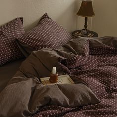 a bottle of medicine sitting on top of a bed next to pillows and a lamp