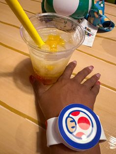 a person's hand with a yellow straw next to a drink on a table