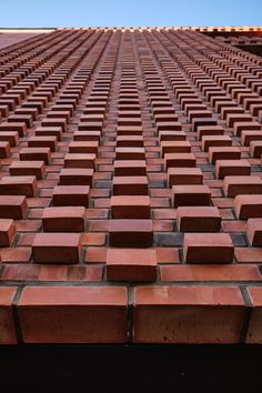 red bricks are arranged in rows on top of each other, with blue sky in the background