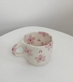 a pink flowered cup sitting on top of a white table