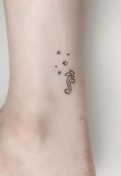 a small tattoo on the ankle of a woman's foot with stars and a seahorse