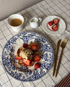 a blue and white plate topped with strawberries next to two cups of hot chocolate