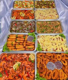 a table topped with trays filled with different types of food