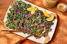 a platter filled with kale, cabbage and lemon wedges on a table