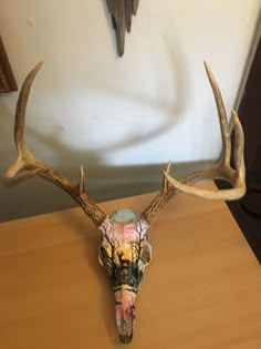 a deer's head with antlers on a table in front of a wall