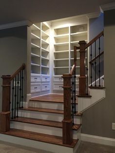 an empty room with wooden stairs and white bookcases