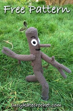 a crocheted toy is standing in the grass with its arms outstretched and eyes wide open