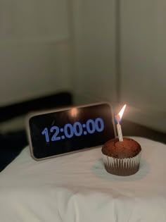 a cupcake sitting on top of a table with a lit candle sticking out of it