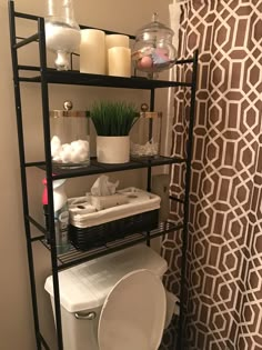 a toilet in a bathroom next to a shelf with candles and other items on it