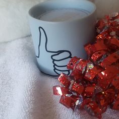 a white cup filled with liquid next to a pile of red cubes