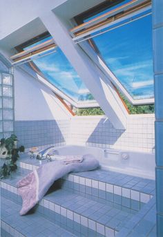 a bathroom with two skylights above the bathtub and tile flooring on the walls