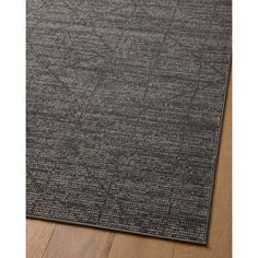 an area rug with dark grey carpeting on top of a wooden floor in front of a