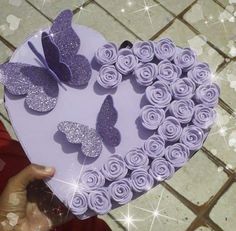 a heart shaped box filled with purple cupcakes and butterflies on top of it