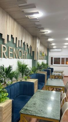 an empty restaurant with blue booths and green plants