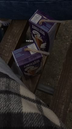 two boxes of milk sitting on top of a wooden table next to a person's leg