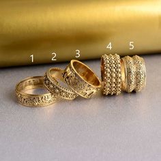 three different types of rings sitting on top of a table next to a gold roll