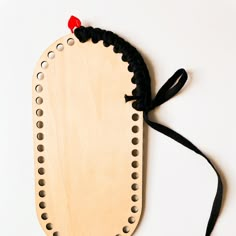 a piece of wood with black string attached to it and a red object in the middle