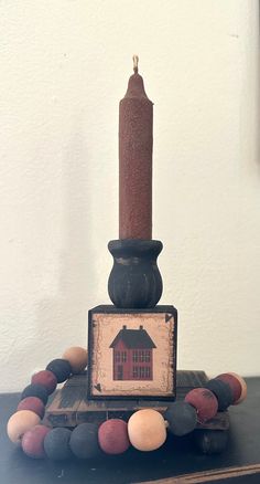 a candle sitting on top of a table next to some balls and a sign with a house