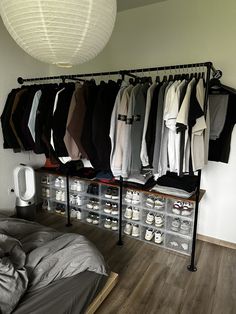 an organized closet with clothes and shoes hanging on the wall, along with a bed