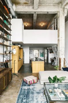 a living room filled with lots of furniture and bookshelves next to a stair case