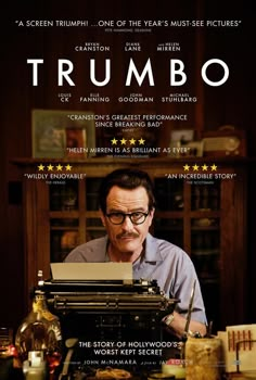 a man sitting at a typewriter in front of a poster for the movie trumpo