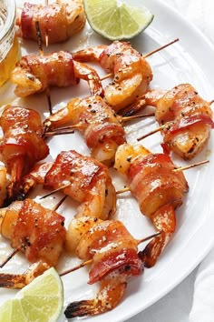 shrimp skewers on a white plate with lime wedges