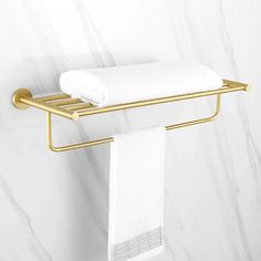 a gold towel rack with two white towels hanging from it's sides on a marble wall