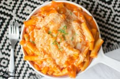 a white bowl filled with pasta and cheese covered in sauce on top of a black and white tablecloth