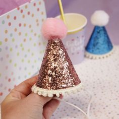 a hand holding a small pink and gold party hat