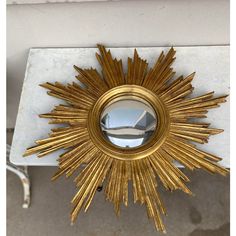 a gold sun mirror sitting on top of a marble table next to a white wall