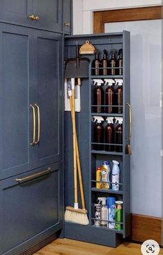 an open cabinet with cleaning supplies and brooms in the bottom section, next to a wooden floor