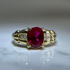 Beautiful red gemstone and diamond ring in a vintage like style and intricate gold band detailing. One large oval cut synthetic ruby centre stone, prong set. Two small pave set diamonds on each side of the centre ruby.  Pre-loved item. Stamped 14KT yellow gold.  Ring Size 9.25 US Weight: 5.110g **FREE shipping within Canada and USA** If you have any questions or concerns, please do not hesitate to contact us. We will be more than happy to help you and answer any inquiries.  We invite you to chec Classic Red Ruby Ring, Oval Cabochon, Classic Red Ruby Ring With Oval Cabochon, Oval Ruby Ring With Diamond And Gemstone Accents, Red Oval Birthstone Ring With Prong Setting, Classic Oval Red Birthstone Ring, Heirloom Ruby Ring With Gemstone Accents, Classic Red Oval Birthstone Ring, Red Diamond Oval Cabochon Ring, Elegant Ruby Rings With Oval Cabochon Center Stone