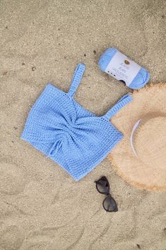 a hat, sunglasses and towel on the sand