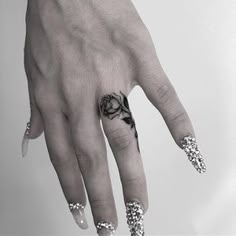 a woman's hand with a rose tattoo on the middle finger and an intricate ring