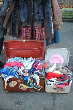 an open suitcase sitting on the ground next to some clothes and other items in it