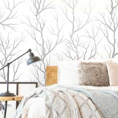 a bed with pillows and blankets on it in front of a wallpapered tree