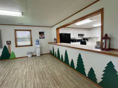 an empty kitchen with christmas trees painted on the wall and wood trim around the counter