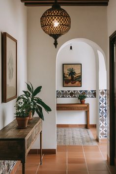 a hallway with an arched doorway and potted plants on the table next to it