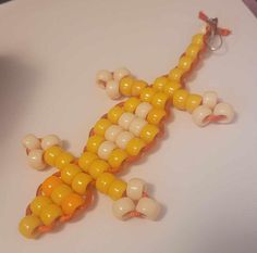 a yellow and white lizard made out of balloons on top of a table next to a cup