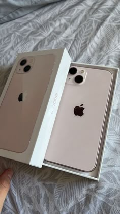 two new iphones in their boxes on a bed