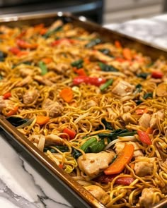 a pan filled with noodles, chicken and veggies