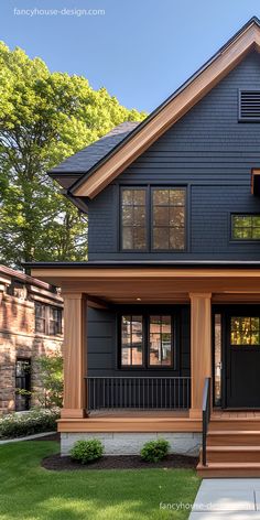 the front view of a two story house with black siding and wood trimmings